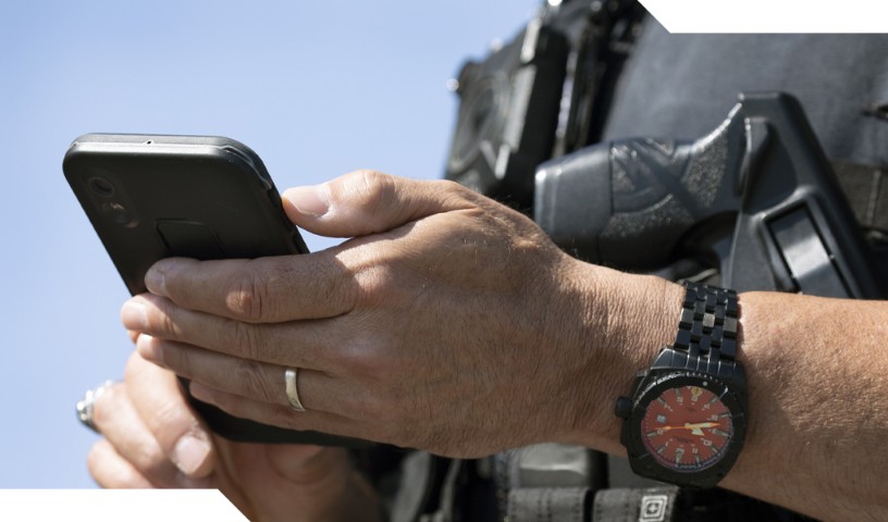 Closeup of law enforcement holding mobile device.