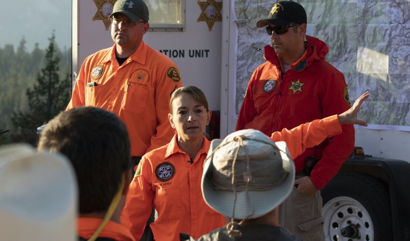 Woman first responder speaks to the crew, pointing to the left