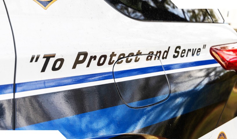 Decal on the side of police car with decal with slogan "To Protect and Serve"
