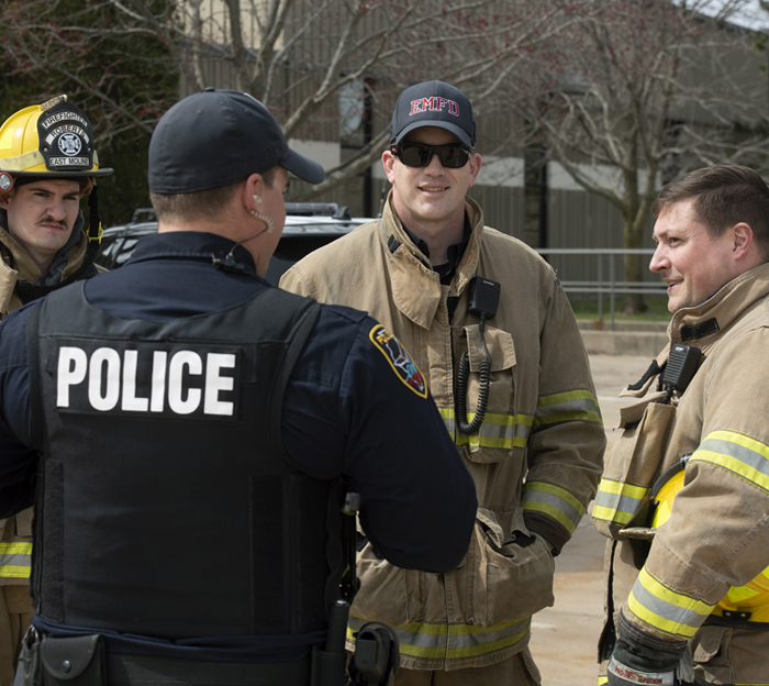 Firemen and police stand together and talk