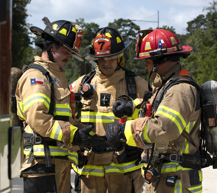 Three Texas firefighters huddle to share information.