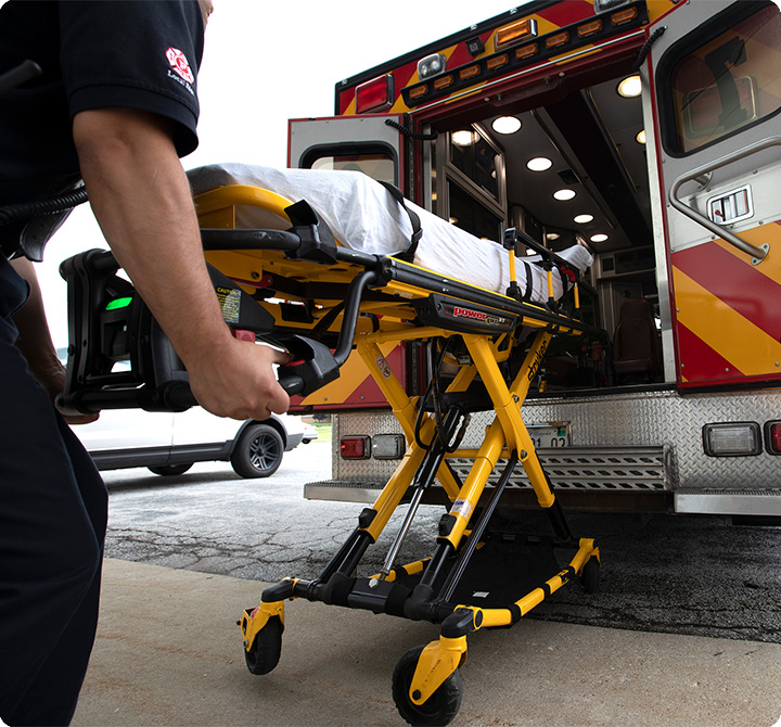 Multiple EMS first responders loading a patient on stretcher into an ambulance