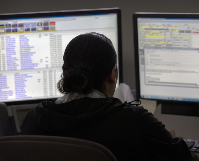 Person sitting in front of two computer monitors