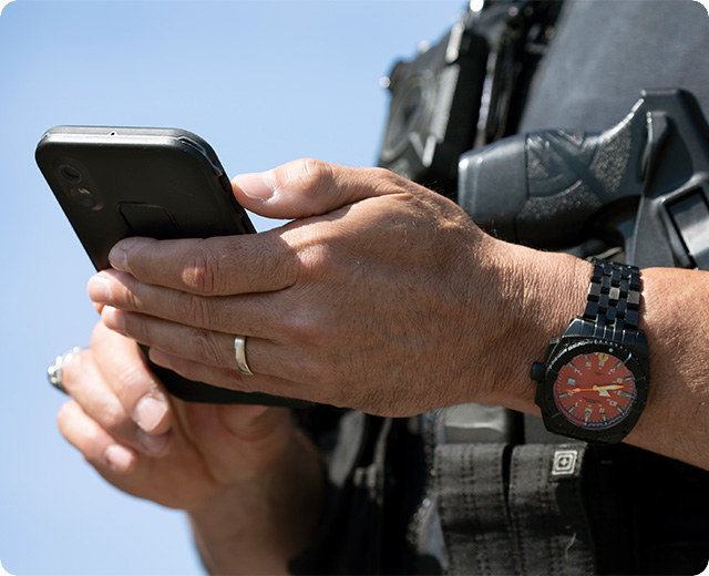 Close up shot of a police officer holding a firstnet phone device in their hand. 