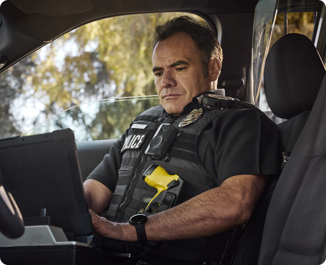 Male officer in patrol car using firstnet connected device 