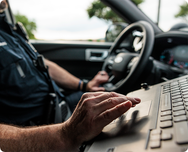 Police officer using laptop inside a vehicle