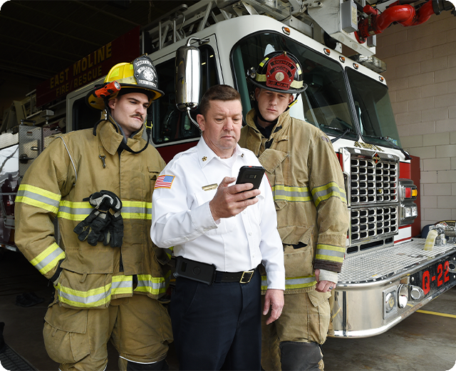 Firefighters at the fire station viewing smart device with the fire chief