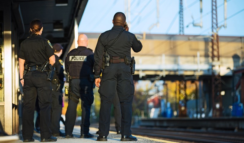 Group of police officers and first responders standing at a light rail station.