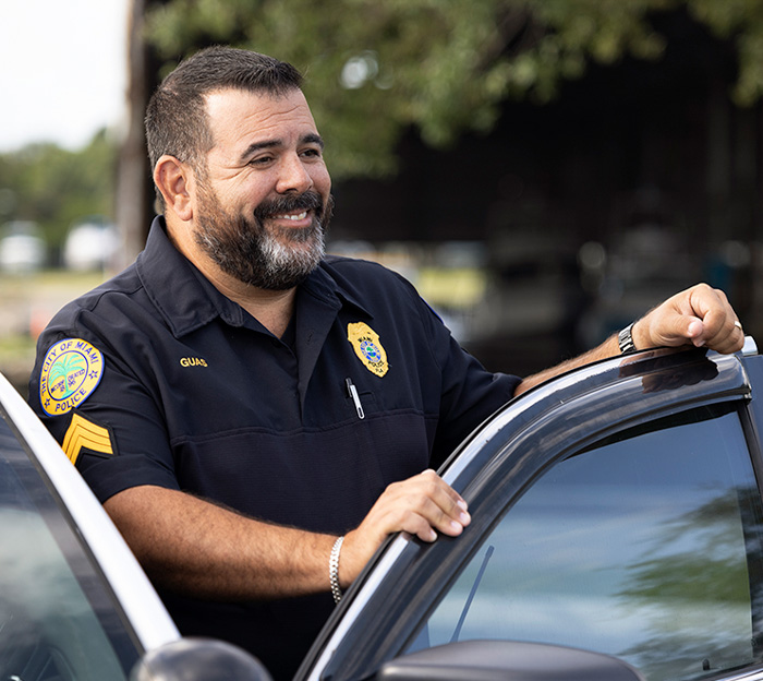 Police officer standing next to car smiling.